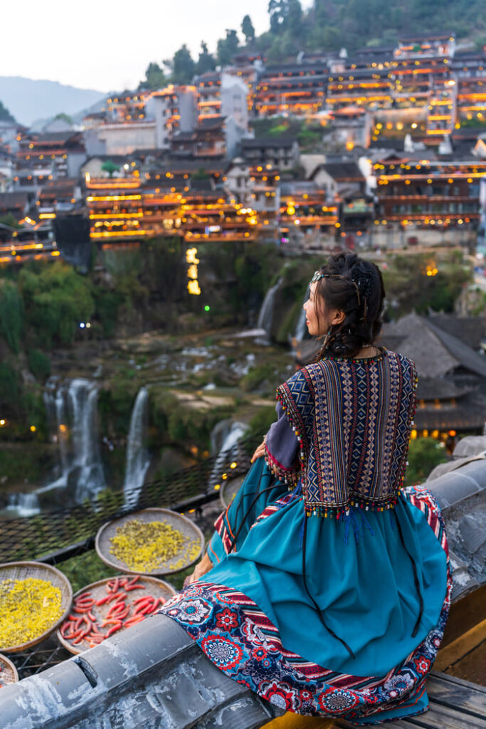 Ciudad China al atardecer observada desde las alturas con una joven china vestida en traje tradicional